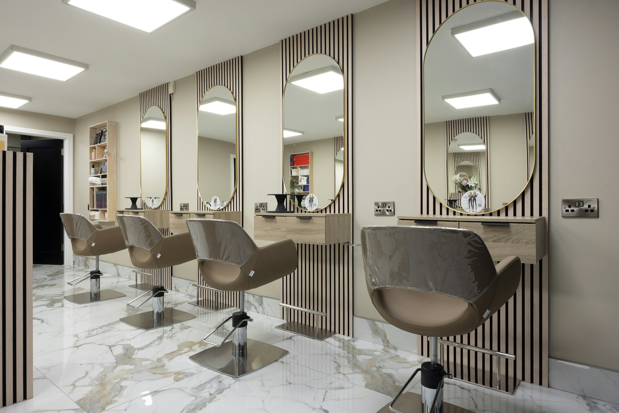 Quiet hair studio interior — warm oak tones and gold mirror frames