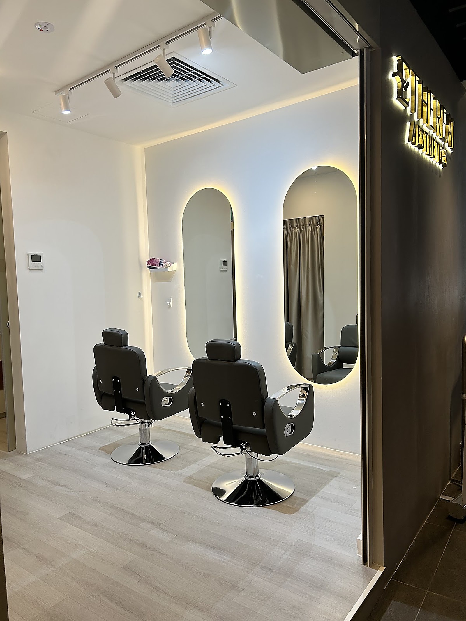Modern salon interior with backlit oval mirrors and warm gold accents