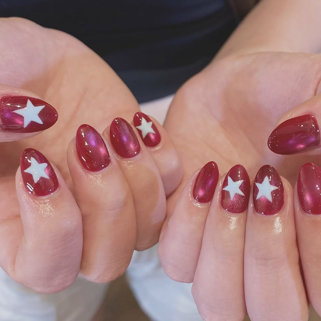 A burgundy nail art set with gold star accents — recent work from every body Maxwell