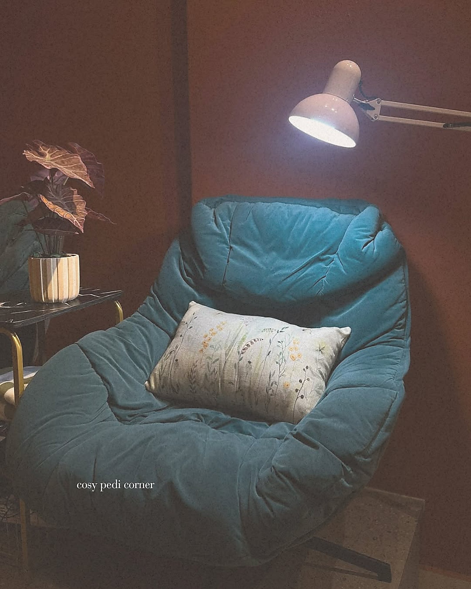 A cozy reading nook inside the every body Maxwell salon — moody lighting, soft textures, intimate seating