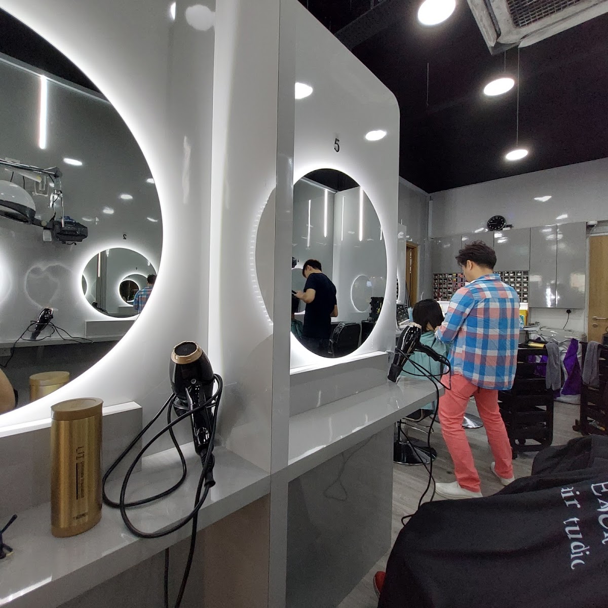 Modern salon studio setup with bright stations and backlit oval mirrors